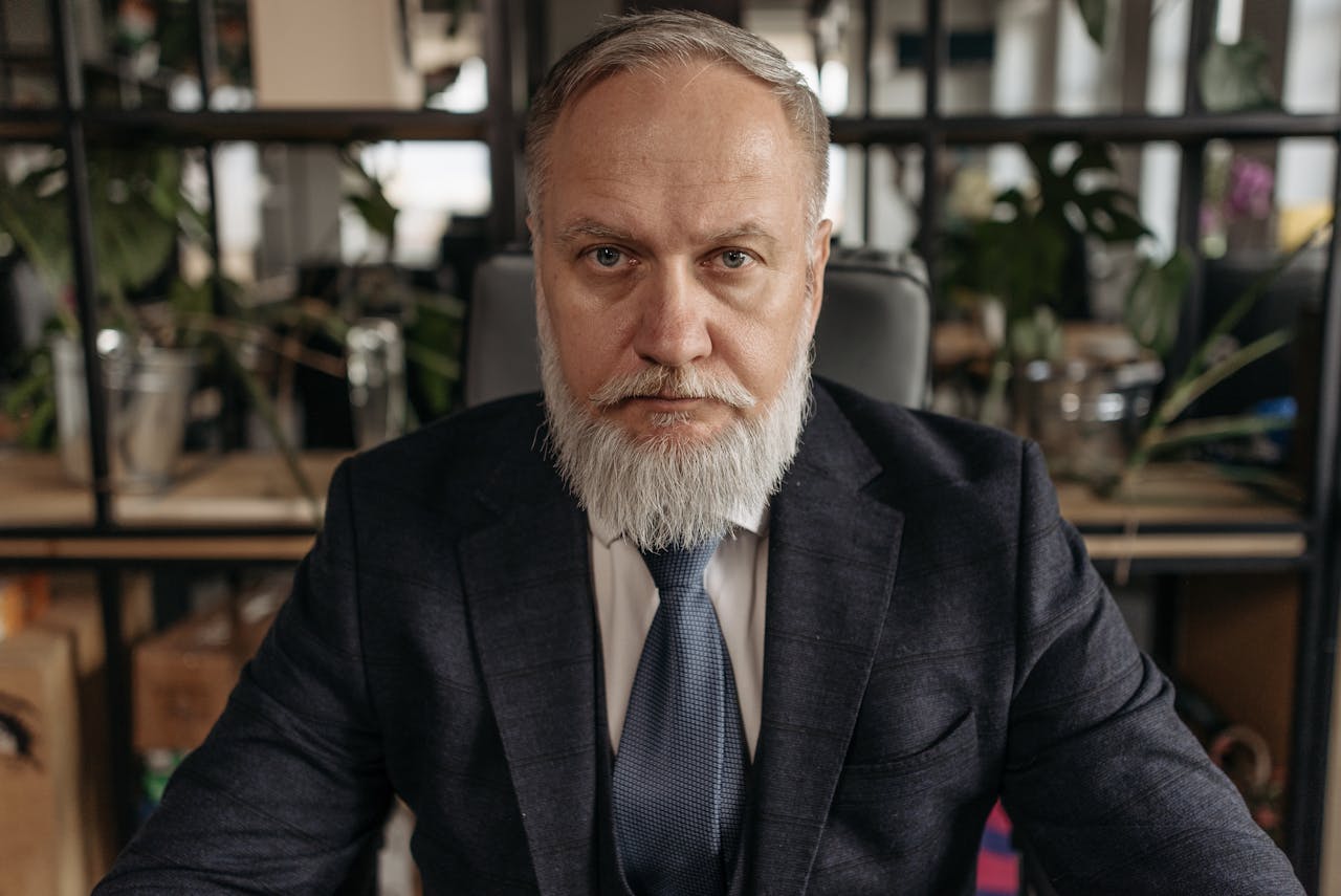 Portrait of a senior businessman with a gray beard in an office environment.